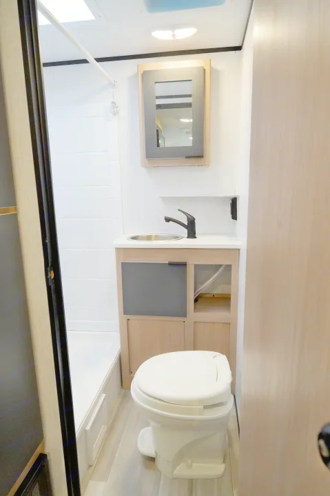 Compact RV rental bathroom featuring a white toilet, modern sink vanity with mirror, and a bright shower area.. Cruiser Rv Corp Hitch 2022