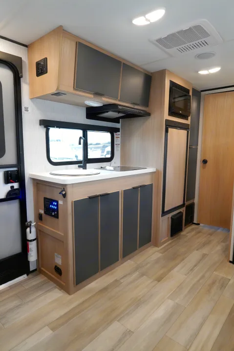 Modern RV rental kitchen interior with light wood cabinets, sink, cooktop, and appliances, offering compact comfort.. Cruiser Rv Corp Hitch 2022