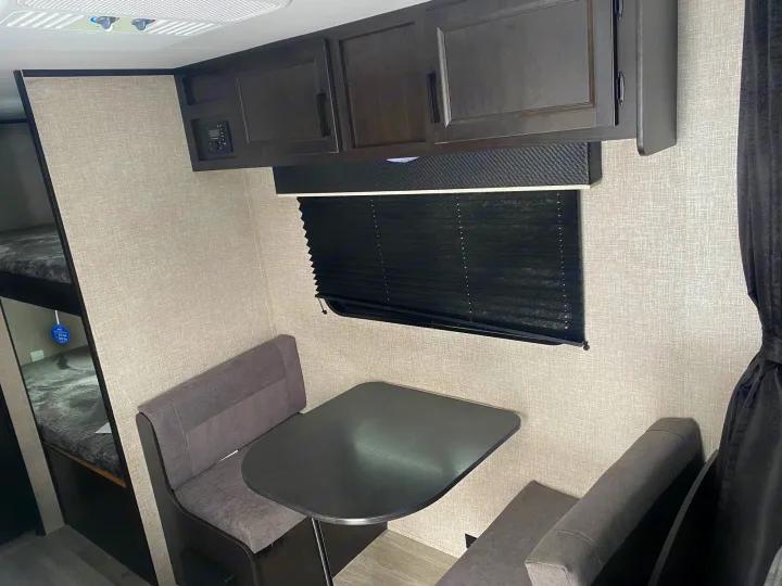 This RV rental interior features a cozy dinette, overhead cabinets, and bunk beds, ideal for travel.. Jayco Jay Flight SLX STX Edition 2022