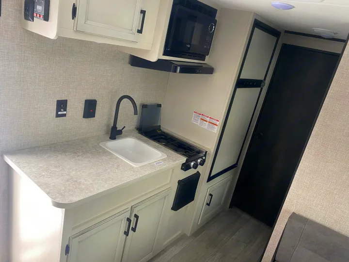 RV rental: A compact kitchen area featuring light countertops, sink, stove, microwave, and fridge for your travels.. Jayco Jay Flight SLX STX Edition 2022
