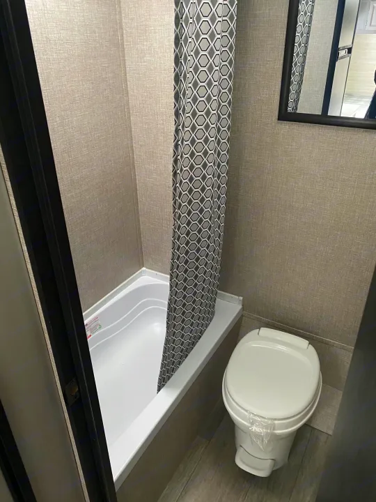 RV rental bathroom interior: Features a compact tub, geometric shower curtain, and toilet. Practical space.. Jayco Jay Flight SLX STX Edition 2022