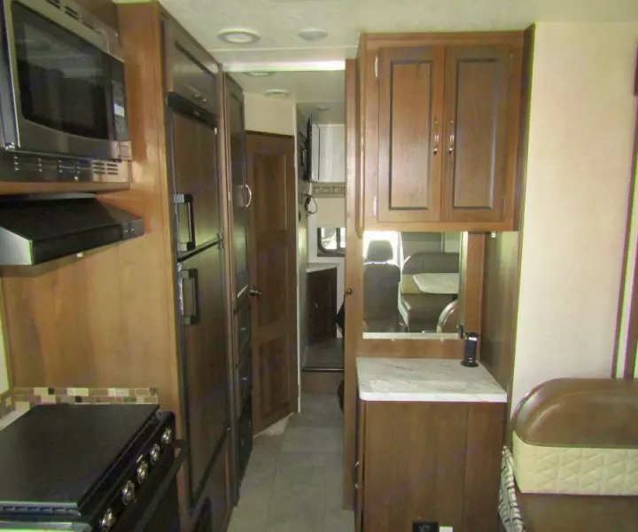 Well-equipped RV rental interior: kitchen with microwave, stove, fridge; mirrored area with counter; and cozy living space.. Coachmen Prism 2022