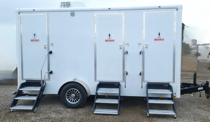 A white multi-stall mobile luxury restroom trailer with steps and signs, available for **RV rental** and events.. Luxury Bathroom 3 Stall 2023