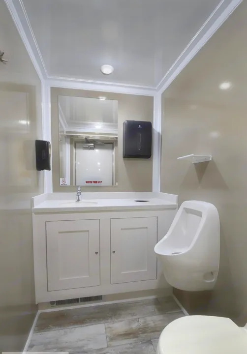 Clean RV rental restroom: modern vanity with sink, mirror, wall dispensers, urinal, and toilet.. Luxury Bathroom 3 Stall 2023