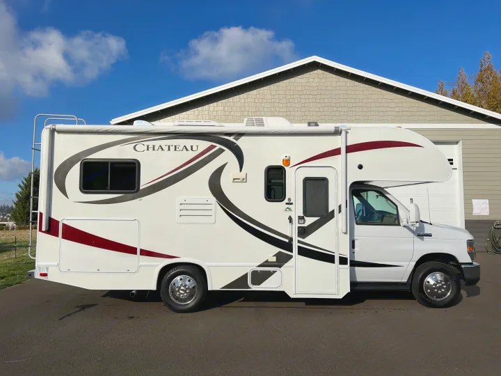 White Chateau Class C RV rental, parked on asphalt under a bright blue sky, ready for travel.. Thor Chateau 2014