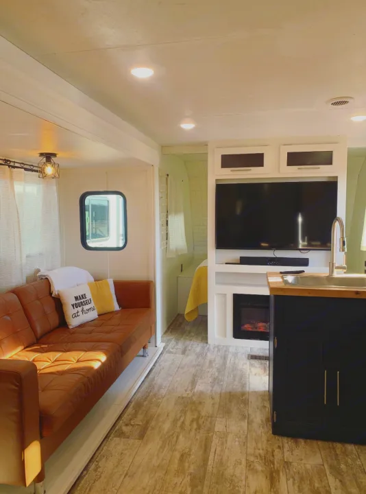 Modern RV rental interior showing a living area with sofa, kitchen island with sink, and cozy bedroom.. Crossroads Zinger 2019