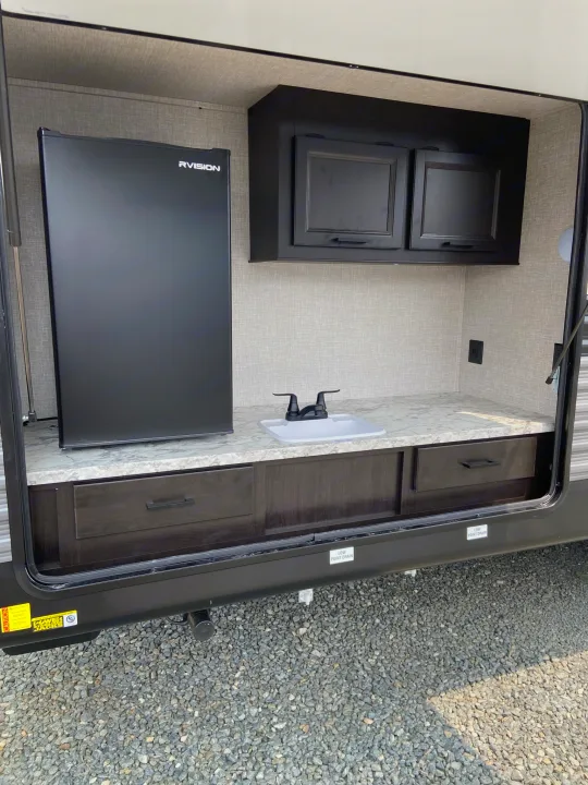 This rv rental features a well-equipped outdoor kitchen with a mini-fridge, sink, and storage, perfect for camping.. Jayco Jay Flight 2022