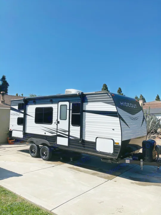 Sunny view of a black & white 'HIDEOUT' travel trailer, ideal for your next RV rental and outdoor adventure.. Keystone Hideout 21BHWE 2021