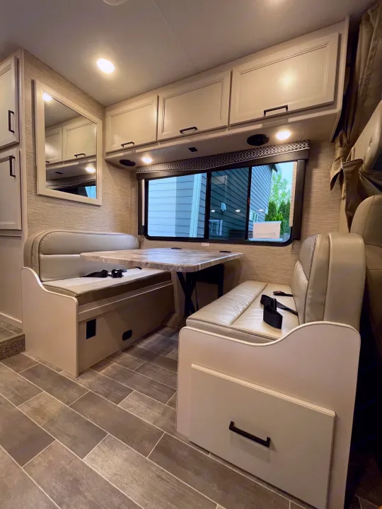 Spacious RV rental interior with a comfortable dinette, storage cabinets, large window, and stylish tiled floor.. Thor Chateau 2022