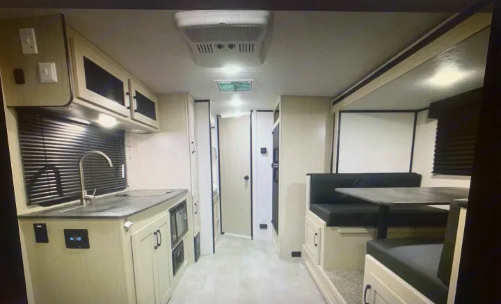 Discover the clean, modern interior of this RV rental, showcasing a fully equipped kitchen and comfortable dinette area.. Coachmen Apex Nano 2021