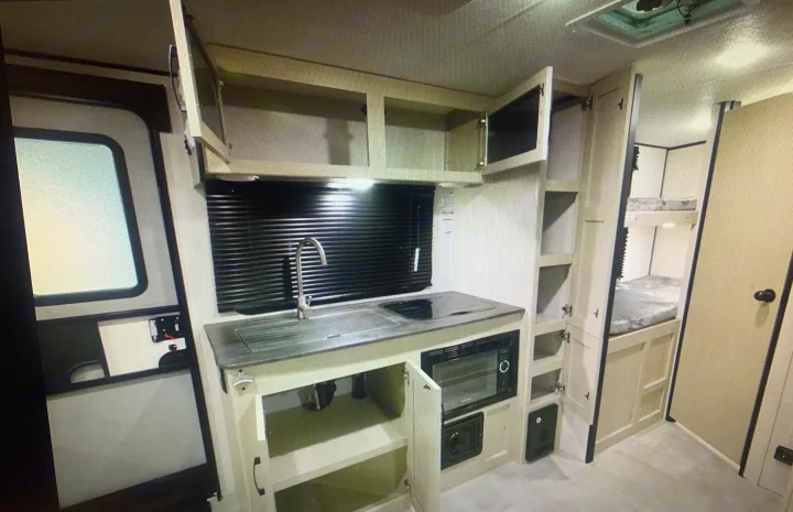 This RV rental's interior features a compact kitchen with sink, cooktop, and microwave, plus space-saving bunk beds.. Coachmen Apex Nano 2021