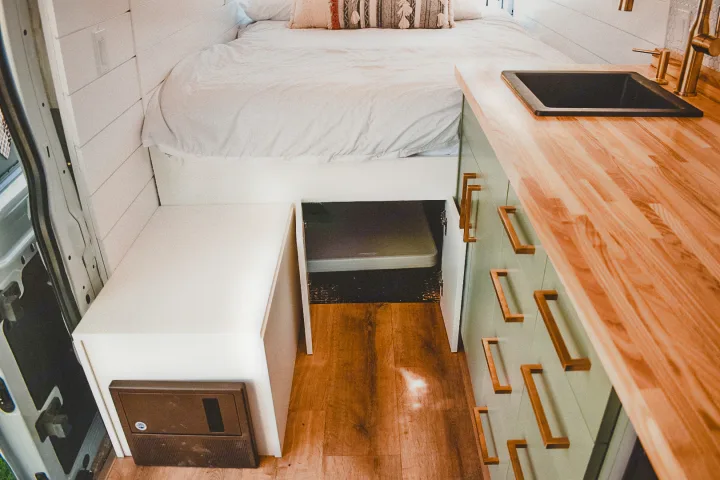 Modern RV rental interior with cozy bed, kitchen counter, sink & storage. Ideal for a comfortable campervan adventure.. Ford Transit 2019