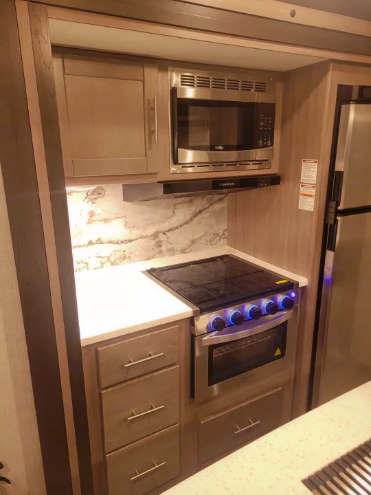 Spacious RV kitchen with modern appliances, including Furrion microwave/hood, Greystone oven, and ample storage. Perfect for your RV rental adventure!. Crossroads Sunset Trail 2023