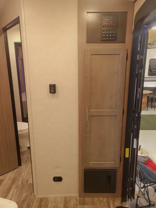 Inside an RV rental: control panel, thermostat, bathroom door, storage, and main entrance. Provides a clear layout.. Crossroads Sunset Trail 2023