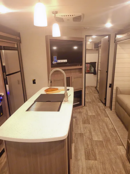 Bright RV rental with a sleek kitchen island, large TV entertainment, and inviting wood-look floors. Great for your next trip!. Crossroads Sunset Trail 2023
