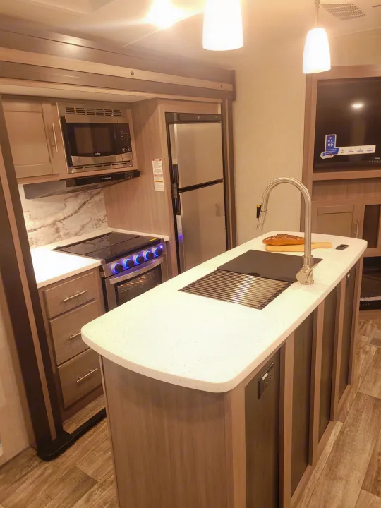 Experience comfort in this modern RV rental kitchen. Features light countertops, stainless appliances, and a full oven.. Crossroads Sunset Trail 2023