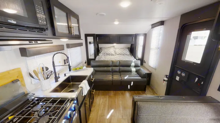 Inside this rv rental: a modern interior with full kitchen (sink, stove, microwave), comfy sofa, and dedicated bed.. Forest River Cherokee Grey Wolf Special Edition 2022
