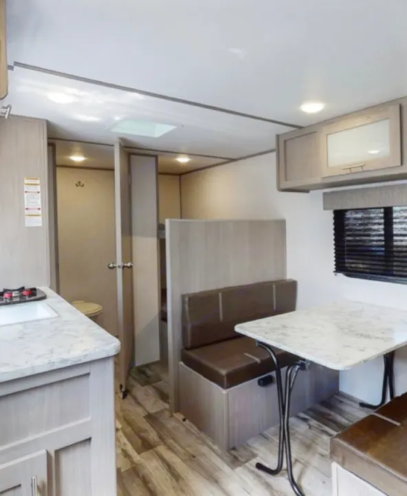 RV rental interior: A bright, clean space with a dinette, compact kitchen, and glimpse of a bathroom/bunk area.. Coleman Other 2021