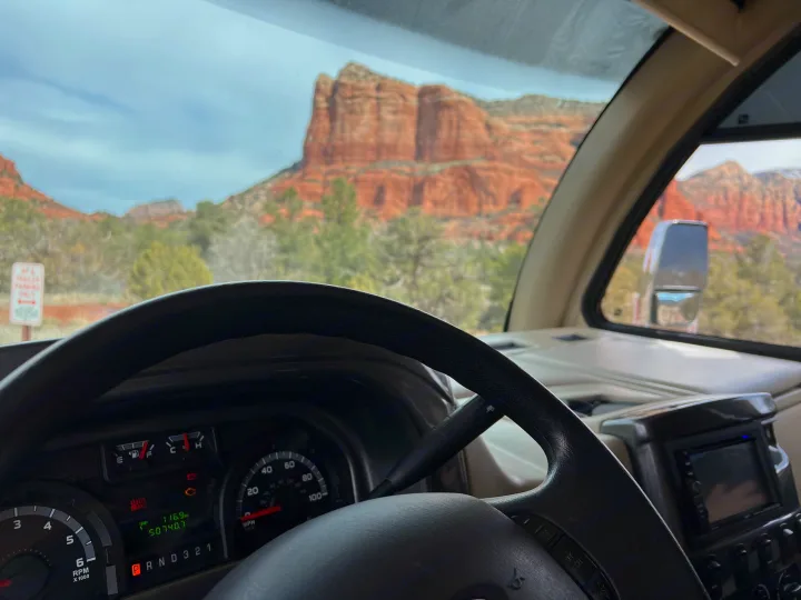 Scenic RV rental view: dashboard shows 50,740.7 miles, parked facing majestic red rock mountains.. Thor Vegas 2016