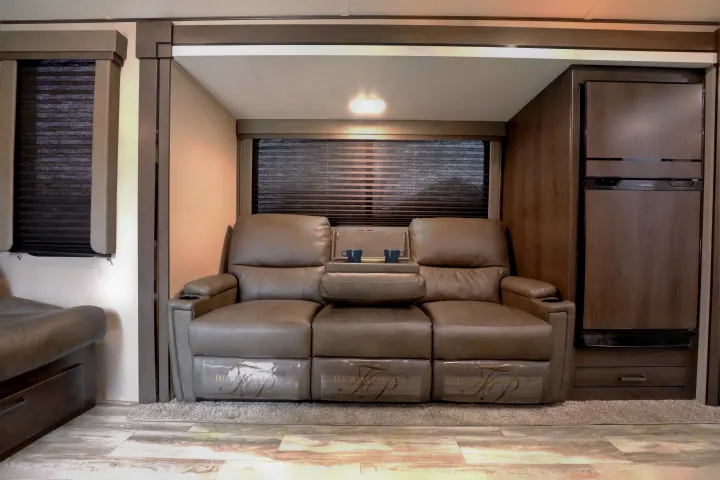 Spacious RV rental interior with comfy recliner sofa, cup holders, privacy blinds, and a built-in refrigerator for your journeys.. Grand Design Transcend Xplor 2022