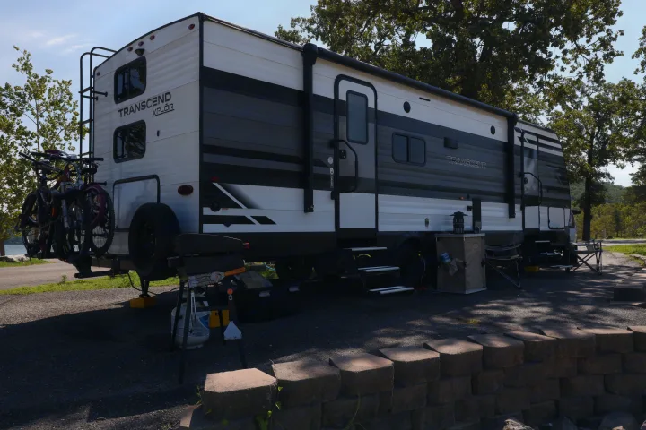 Transcend XPLÔR RV rental at a scenic campsite, ready for adventure with bikes and outdoor gear.. Grand Design Transcend Xplor 2022