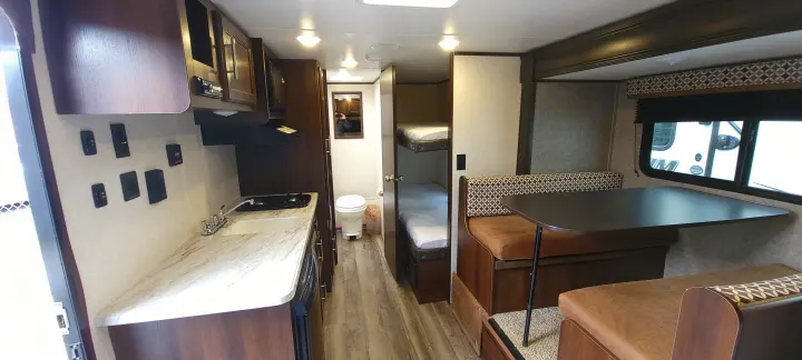 View of an RV rental interior showcasing a compact kitchen, dinette, bunk beds, and a private bathroom.. Jayco Jay Flight SLX 184 BS 2019