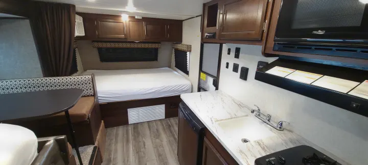 RV rental interior showcasing compact kitchen, comfortable bed, and dining area. Ideal for travel.. Jayco Jay Flight SLX 184 BS 2019
