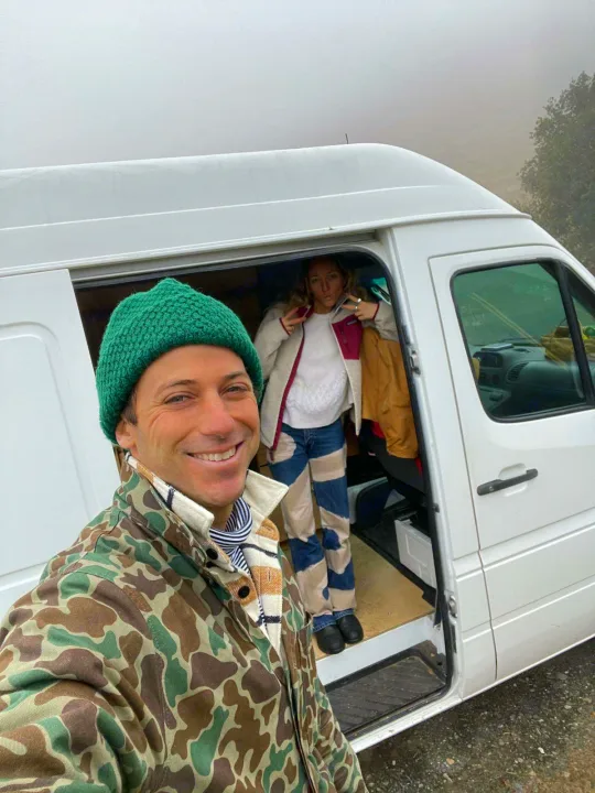 A man in a green beanie takes a selfie with a woman inside their white rv rental van, ready for a trip.. Mercedes Sprinter 2006