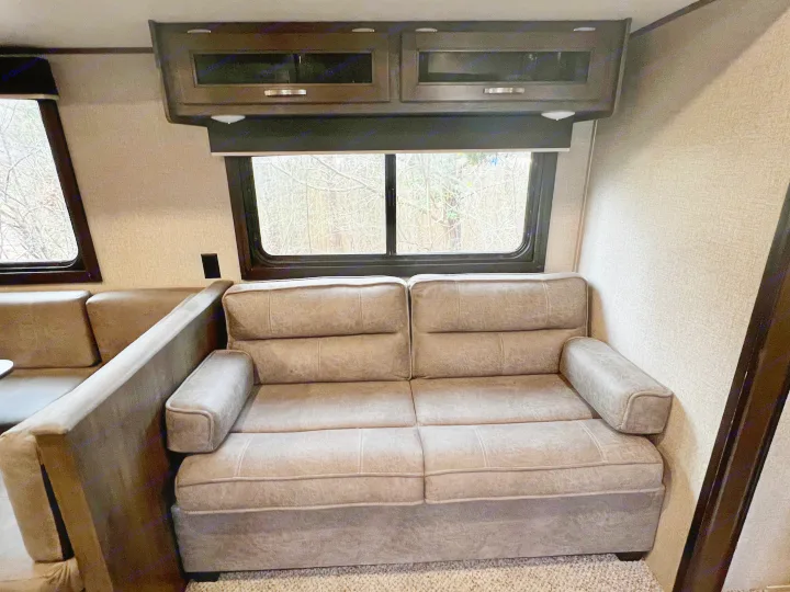 RV rental: Interior view of living area with sofa, large windows showing bare trees, and overhead cabinets.. Jayco Jay Flight SLX 2020