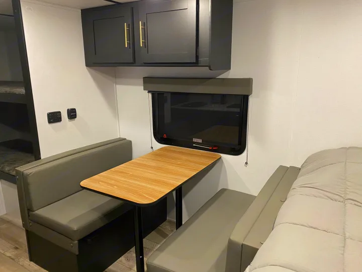 Cozy RV rental interior with a dinette, overhead cabinets, bunk beds, and a sleeping area, perfect for travel.. Keystone Springdale 1800BH 2022