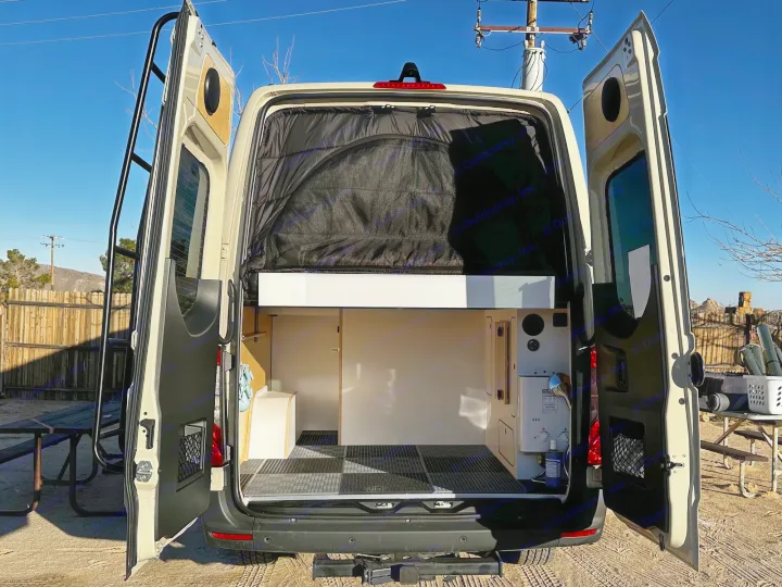 Open rear doors of this RV rental reveal a functional camper van interior with raised bed, storage, and utility area.. VanCraft VanCraft Class B 2022