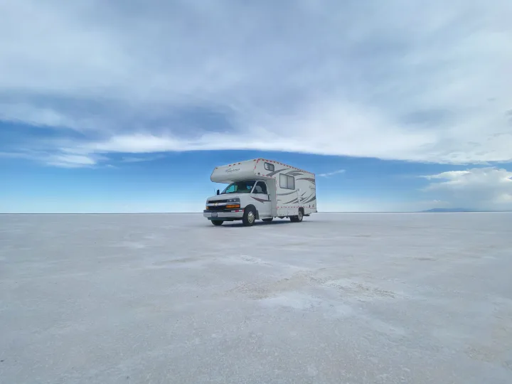 An RV rental sits on the immense Bonneville Salt Flats under a wide, cloudy sky, highlighting a remote adventure.. Coachmam Freelander 21QB 2012