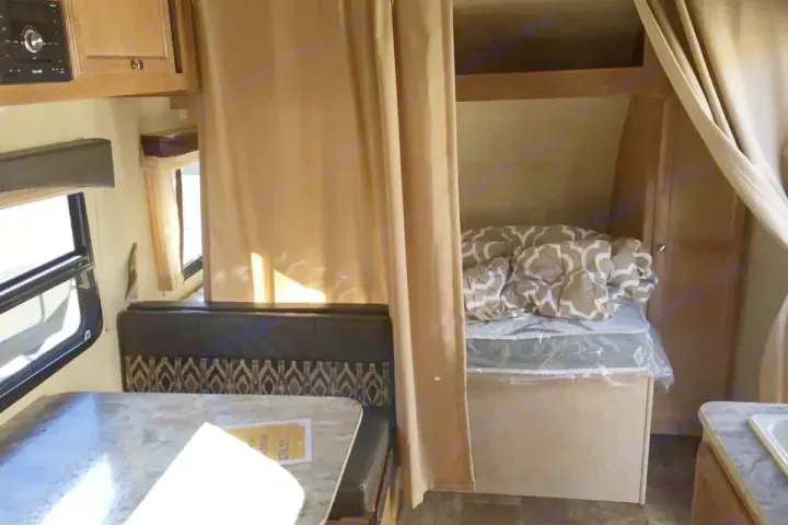 Cozy RV rental interior: dinette, private sleeping area with curtain, and compact kitchen space.. Gulf Stream Other 2018