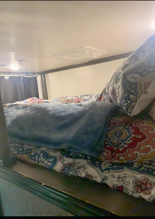 Cozy bunk bed interior in an RV rental, featuring colorful patterned bedding and a plush blue blanket for comfortable travel.. Heartland Elkridge 2019
