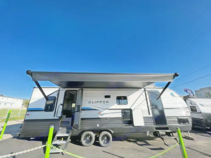 A white and black Clipper travel trailer with an extended awning and steps, under a clear blue sky. Ideal for rv rental.. Coachmen Clipper 262 BH C 2023