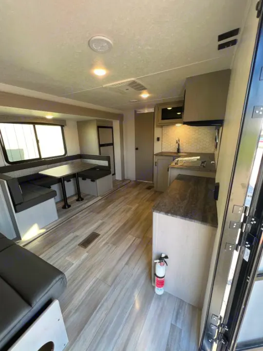 Light-filled, modern RV rental interior with kitchen, dinette, wood-look flooring, and rear garage area.. Coachmen Clipper 262 BH C 2023