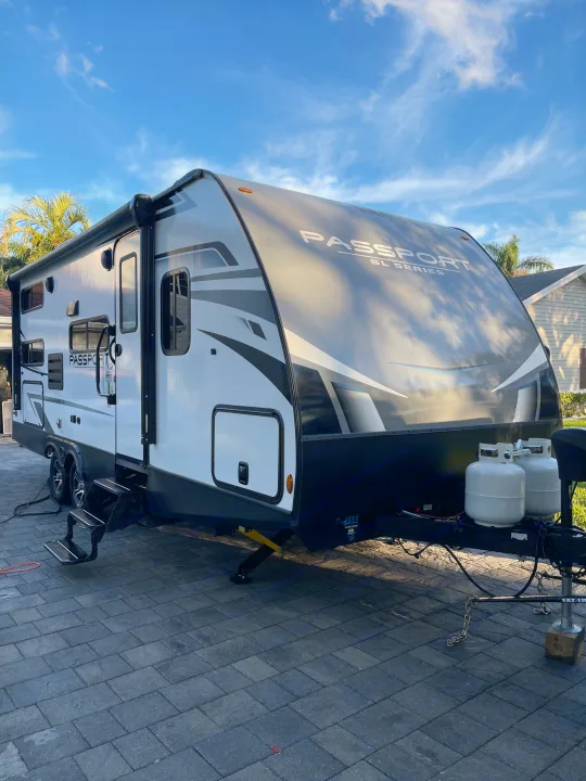 Discover your next RV rental adventure! This Passport SL Series travel trailer is fully set up, parked on a paved driveway.. Keystone RV Passport SL 2022