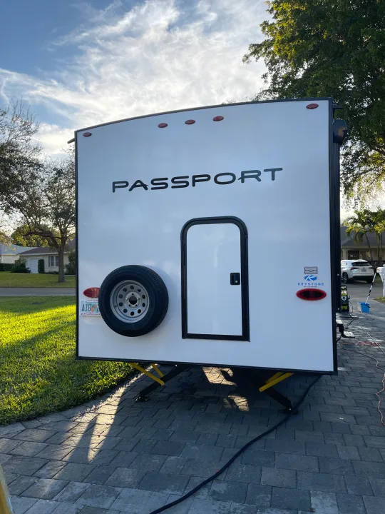White Passport RV, ready for rv rental and travel. Parked on a paved driveway at home, bathed in sunlight.. Keystone RV Passport SL 2022