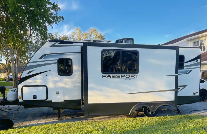 White Passport travel trailer, a spacious RV rental, parked on a driveway with slide-out extended, ready for adventures.. Keystone RV Passport SL 2022