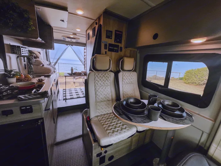 Spacious RV rental interior with kitchen, dining setup, and scenic ocean views from the screened rear opening. Ready for adventure!. Winnebago Solis 59PX 2023