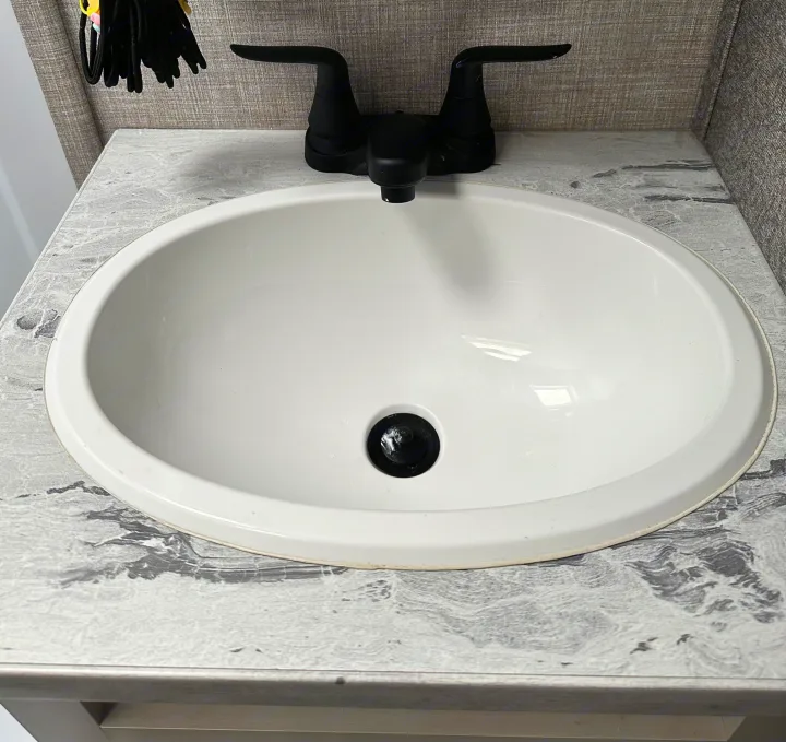 Clean bathroom sink and black faucet in an RV rental. Features a gray patterned vanity for a functional travel space.. Jayco Jay Feather Micro 2022