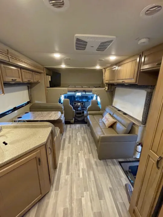 Inside a modern rv rental: open living space with dinette, sofa, and kitchen counter. Bright and ready for travel.. Thor Motor Coach Four Winds 2018