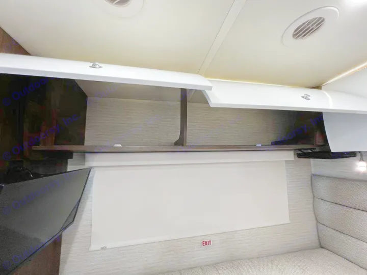 A bright RV rental interior with open white overhead cabinets, a TV, a pull-down exit shade, and cozy seating.. Winnebago View 2023
