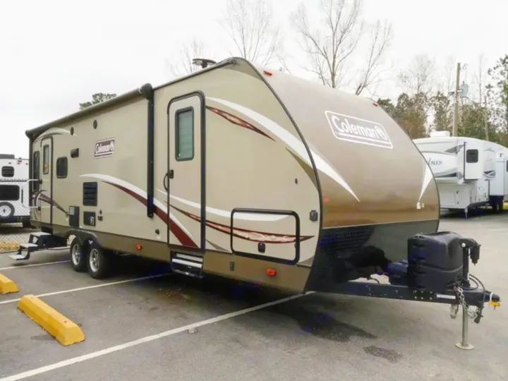 Explore the open road with this beige & brown Coleman travel trailer. Perfect for RV rental, parked on asphalt.. Dutchmen Coleman Light 2018