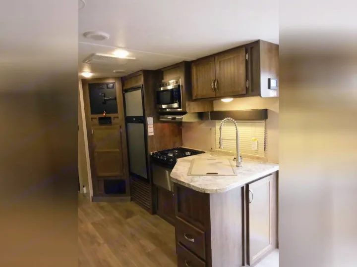 Inside an RV rental: a well-equipped kitchen with gas range, microwave, fridge, sink, and ample cabinetry, ready for your adventures.. Dutchmen Coleman Light 2018