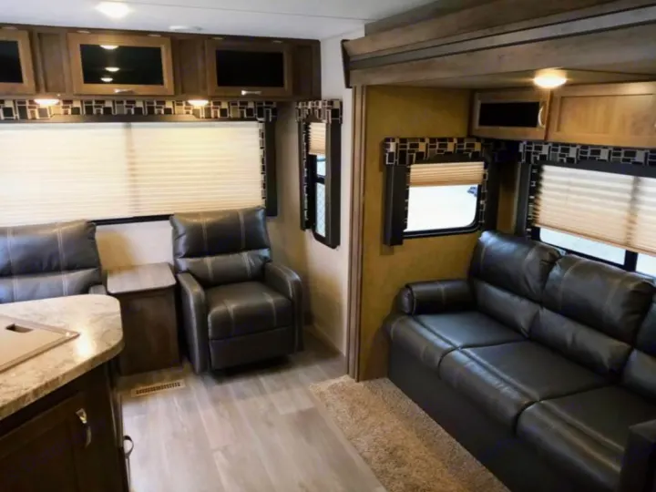 Comfortable RV rental living area featuring leather seating, a wood end table, and a kitchen counter.. Dutchmen Coleman Light 2018
