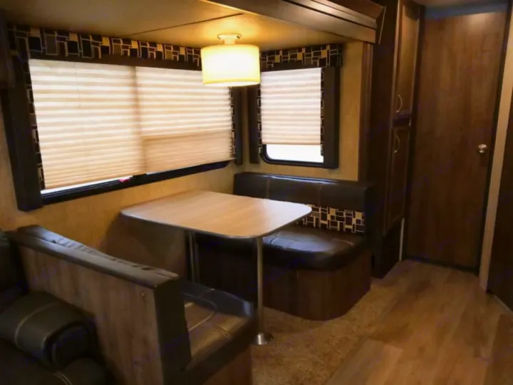 RV rental interior showcasing a dinette booth, windows with blinds, and efficient use of space.. Dutchmen Coleman Light 2018