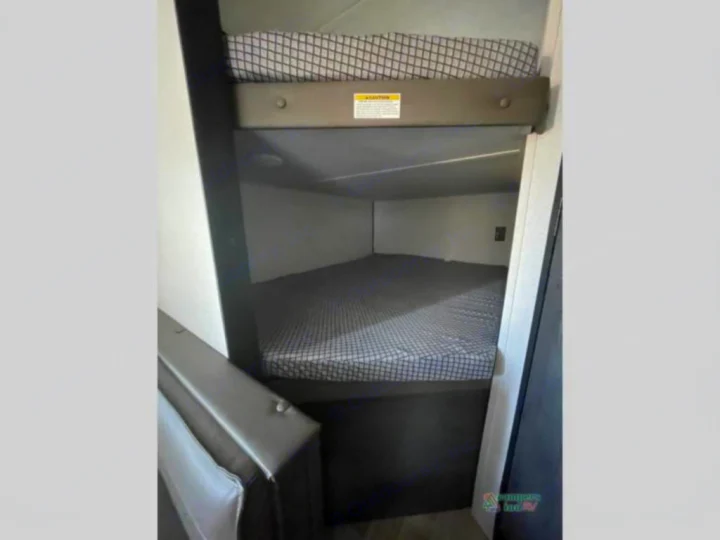 Cozy bunk beds in this RV rental offer two sleeping areas with checkerboard mattresses and a safety rail.. Keystone RV Hideout 2022