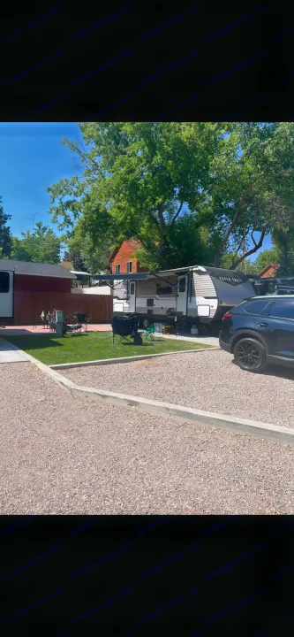 Relaxing at an RV rental campsite. A large travel trailer with an extended awning, SUV, and grass patio setup are visible.. Aspen Trail Aspen Trail Trailer 2021
