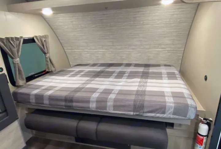 RV rental interior: A cozy sleeping area with a plaid bed over a dinette bench, complete with a window. Perfect for your camper adventure.. Forest River Coachmen Catalina Summit 2022